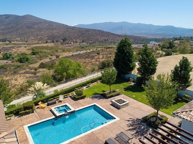 view of swimming pool with a mountain view, a fire pit, a patio, and an in ground hot tub