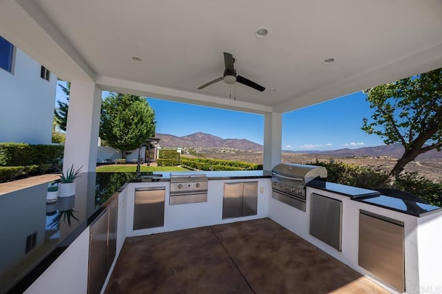 view of patio with area for grilling, a mountain view, sink, and ceiling fan