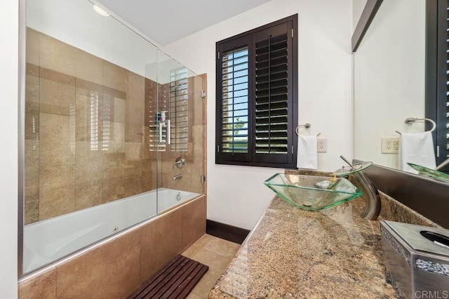 bathroom featuring tile patterned flooring, sink, and bath / shower combo with glass door