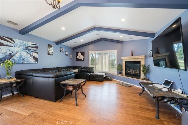 living room with vaulted ceiling with beams, light wood-type flooring, and a fireplace