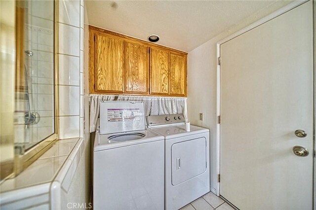 laundry area featuring washer and dryer, light tile patterned flooring, and a textured ceiling