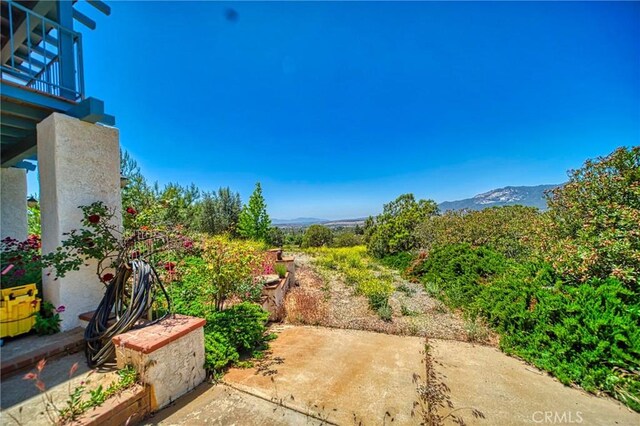 view of yard featuring a mountain view, a balcony, and a patio area