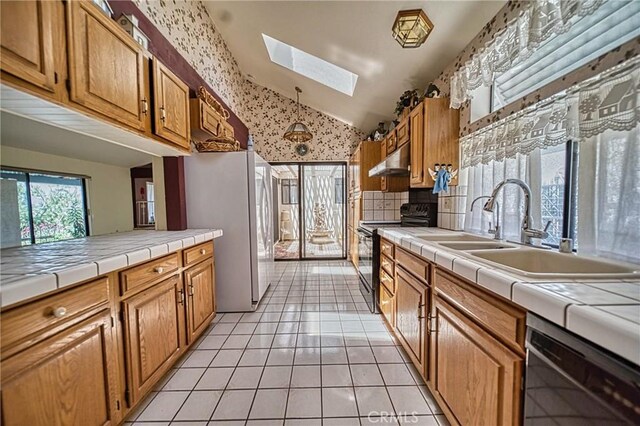 kitchen featuring tile countertops, black electric range oven, dishwasher, and white refrigerator