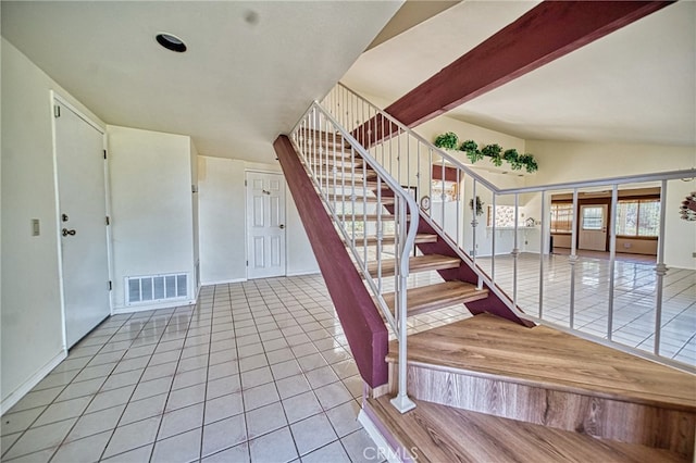 stairway with tile patterned floors and vaulted ceiling