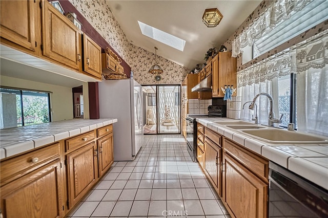 kitchen with tile countertops, dishwasher, black electric range, lofted ceiling with skylight, and sink