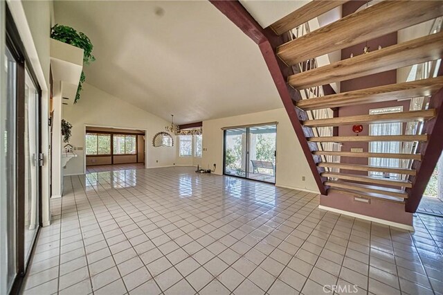 unfurnished living room with light tile patterned floors, high vaulted ceiling, a wealth of natural light, and an inviting chandelier