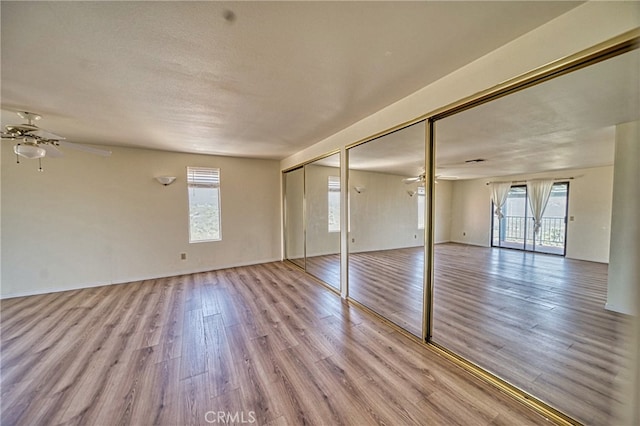 empty room with a healthy amount of sunlight, light wood-type flooring, and ceiling fan