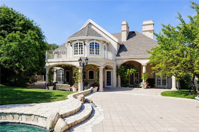 view of front facade featuring a balcony and a front lawn