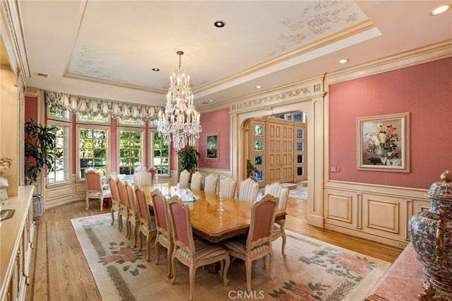 dining space with light wood-type flooring, crown molding, and a tray ceiling