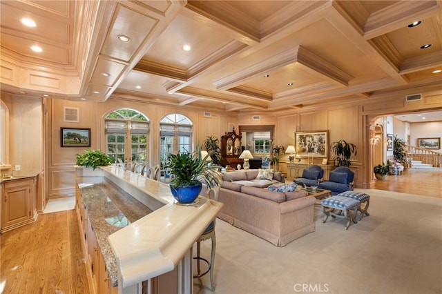 living room featuring coffered ceiling, crown molding, and light hardwood / wood-style flooring