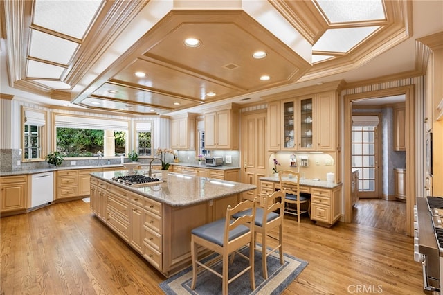 kitchen featuring light wood-type flooring, light stone counters, ornamental molding, a center island with sink, and dishwasher