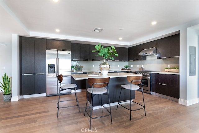 kitchen with a kitchen island, ventilation hood, stainless steel appliances, and light hardwood / wood-style floors