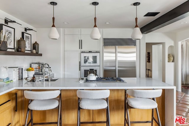 kitchen with stainless steel appliances, pendant lighting, white cabinets, and a breakfast bar