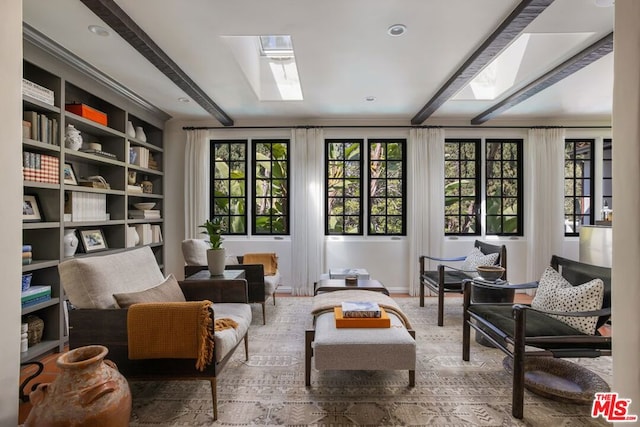 living area featuring a healthy amount of sunlight and beamed ceiling