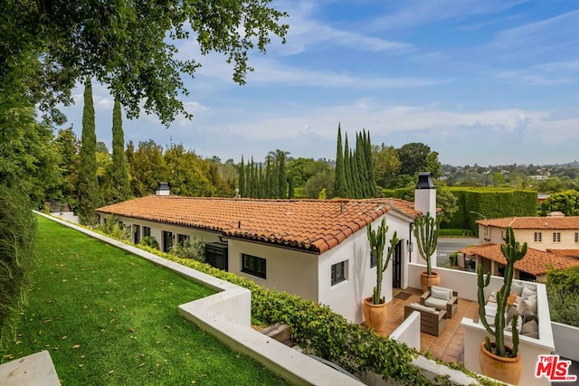 rear view of house with a yard, an outdoor living space, and a patio