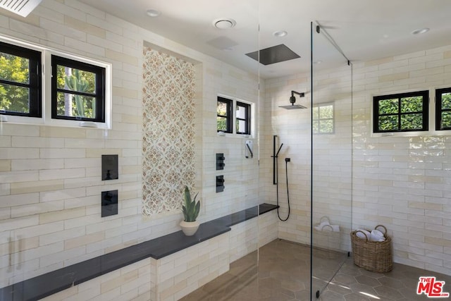 bathroom featuring a wealth of natural light, a tile shower, and tile patterned flooring