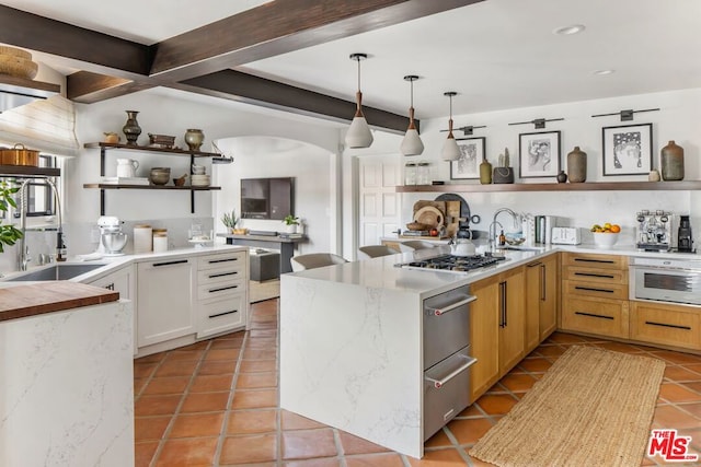 kitchen featuring stainless steel gas stovetop, light tile patterned floors, white cabinetry, and decorative light fixtures