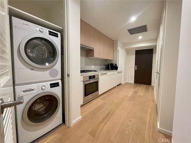 interior space with stacked washer / drying machine, sink, and light hardwood / wood-style floors