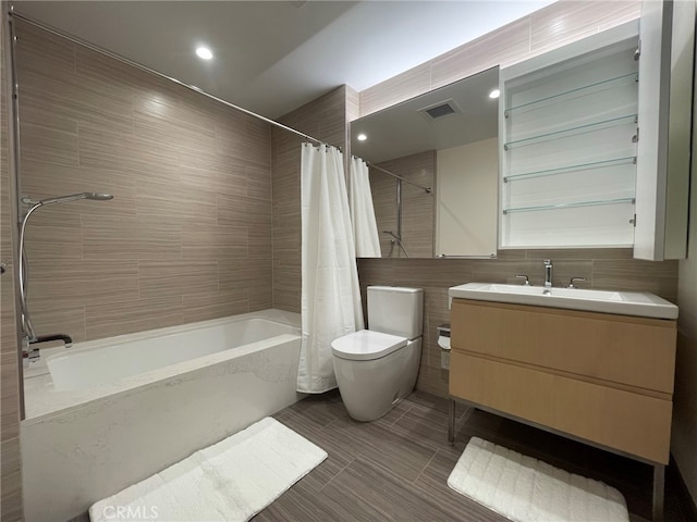 full bathroom featuring toilet, shower / tub combo with curtain, vanity, and tile walls