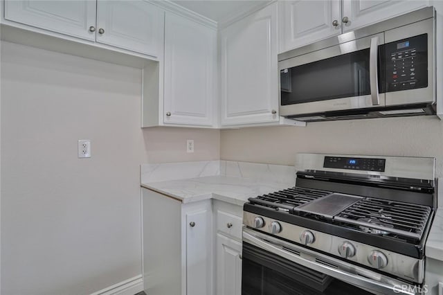 kitchen with appliances with stainless steel finishes, white cabinetry, and light stone counters