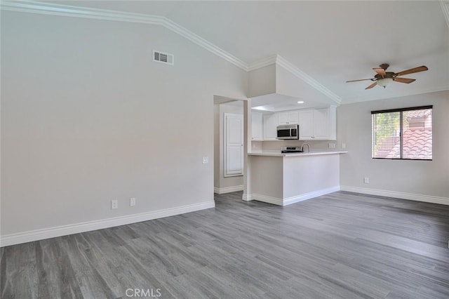 unfurnished living room featuring hardwood / wood-style flooring, ceiling fan, crown molding, and vaulted ceiling