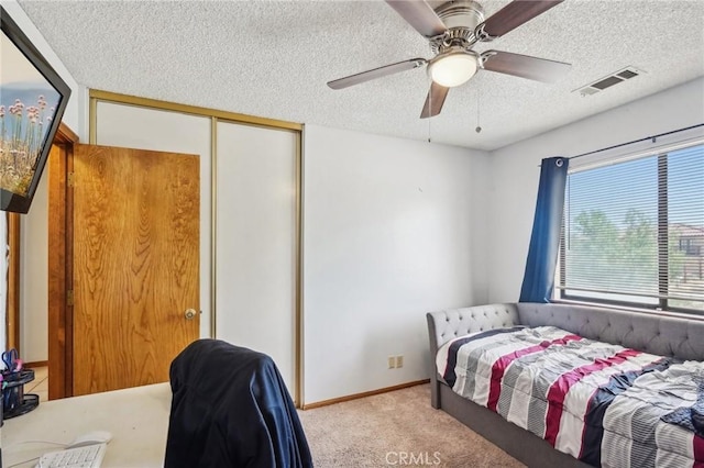 carpeted bedroom featuring ceiling fan, a closet, and a textured ceiling