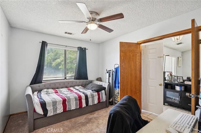 bedroom featuring ceiling fan, light carpet, and a textured ceiling