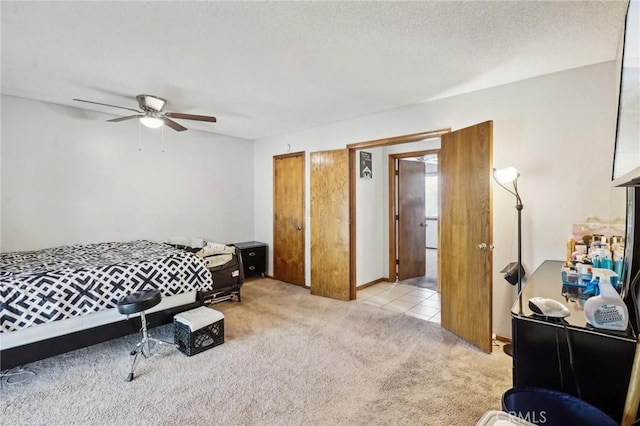 carpeted bedroom with a textured ceiling, two closets, and ceiling fan