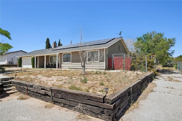 ranch-style home featuring solar panels and a garage