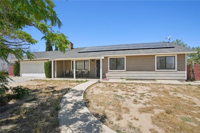 ranch-style home with a porch, solar panels, and a garage