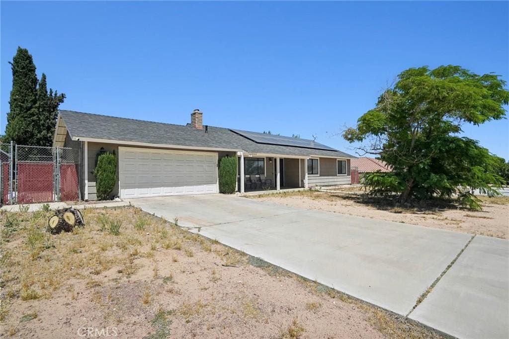 ranch-style house featuring a garage and solar panels