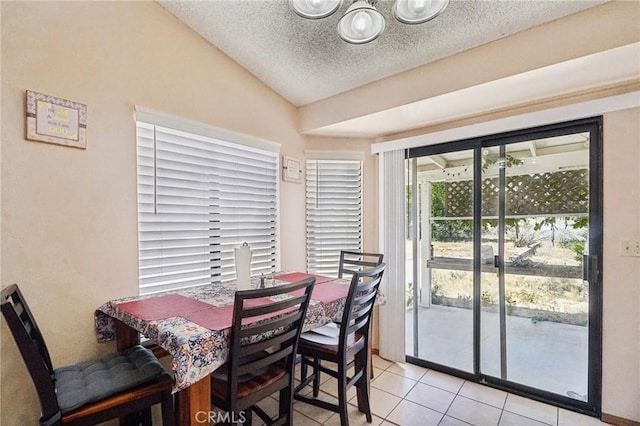 dining room with a textured ceiling, light tile patterned flooring, and lofted ceiling