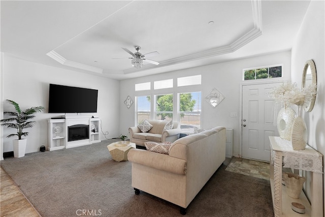 carpeted living room with crown molding, a tray ceiling, a healthy amount of sunlight, and ceiling fan