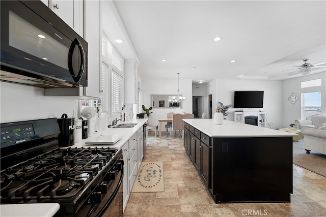 kitchen featuring a center island, white cabinets, black appliances, and decorative light fixtures