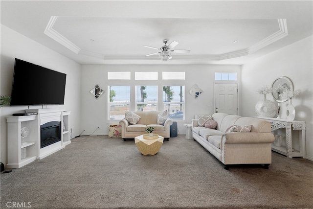 living room with a tray ceiling, carpet, and ceiling fan