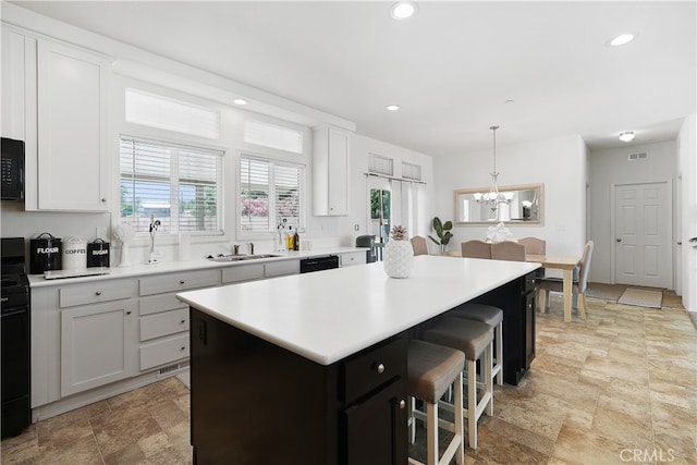 kitchen with white cabinets, black appliances, sink, and a kitchen island