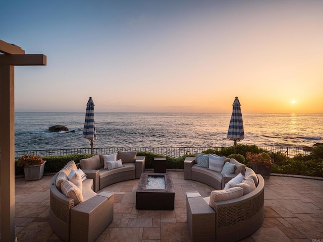 patio terrace at dusk with a water view and an outdoor living space with a fire pit