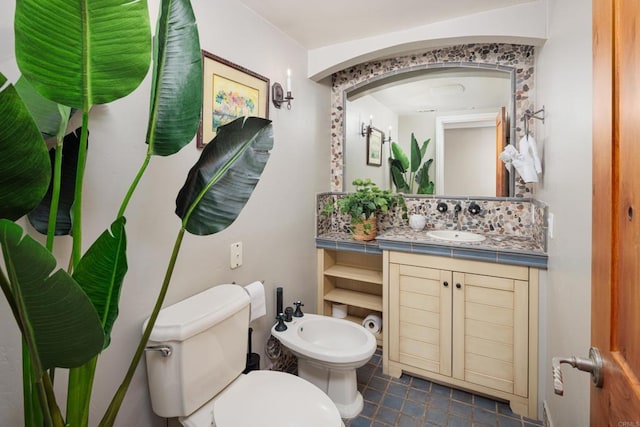 bathroom with tile patterned floors, vanity, backsplash, toilet, and a bidet