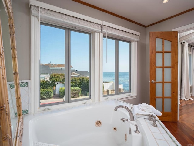 bathroom featuring plenty of natural light, a bath, ornamental molding, and a water view