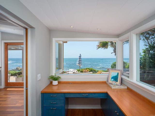 interior space with a water view, vaulted ceiling, and built in desk