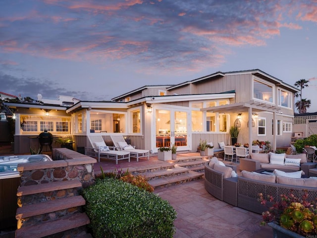 back house at dusk with solar panels, a patio area, and an outdoor hangout area