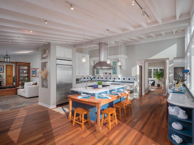 dining area featuring track lighting, beam ceiling, and dark wood-type flooring