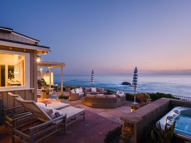 patio terrace at dusk featuring a water view, an outdoor hangout area, and a grill