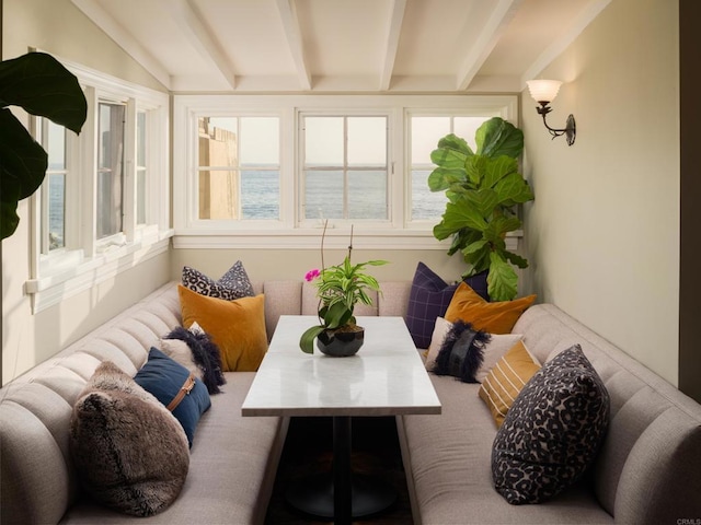 sunroom / solarium with plenty of natural light, a water view, and vaulted ceiling with beams