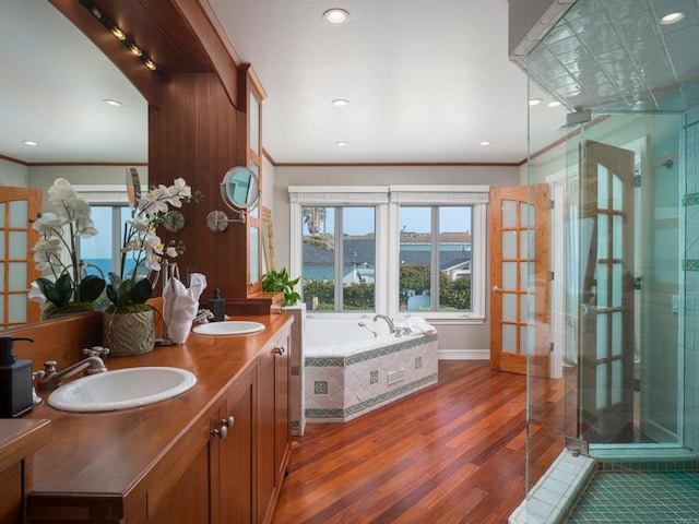 bathroom with wood-type flooring, crown molding, independent shower and bath, a water view, and vanity