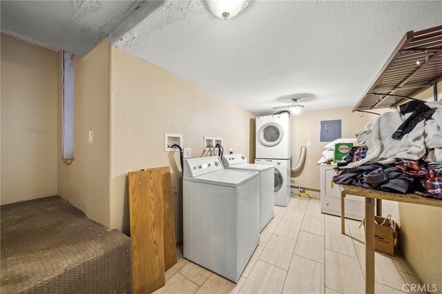 clothes washing area featuring a textured ceiling, stacked washing maching and dryer, and electric panel