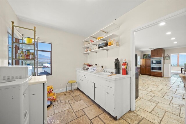 kitchen with white cabinetry, sink, double oven, washer / clothes dryer, and crown molding