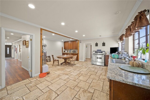 kitchen featuring stainless steel range, light stone counters, crown molding, and sink