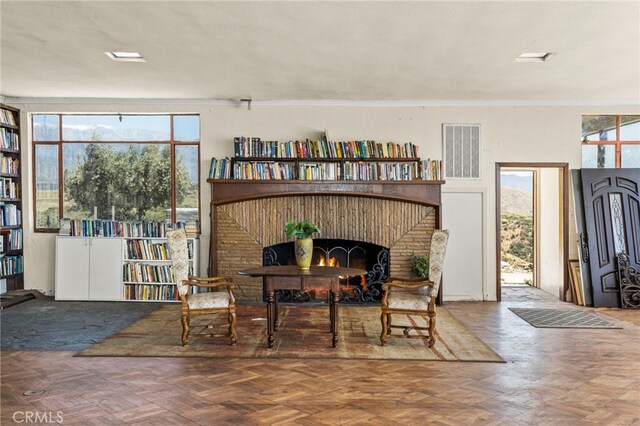 sitting room with a textured ceiling, crown molding, parquet floors, and a fireplace