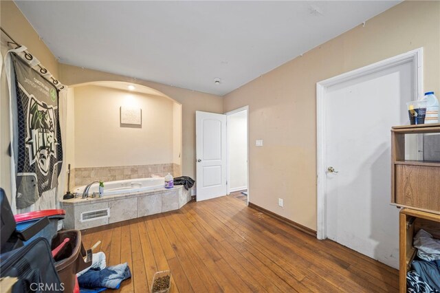 interior space with tiled tub and hardwood / wood-style flooring